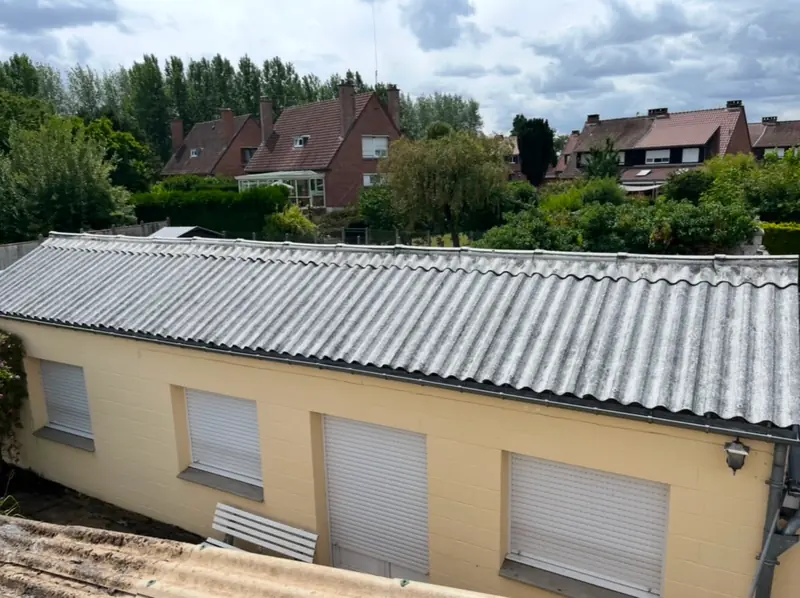 Toiture en bac acier gris ondulé sur maison claire avec volets