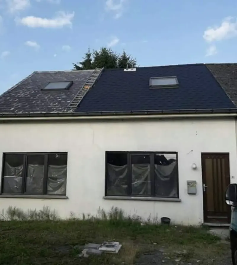 Maison avec toiture rénovée en ardoises foncées et fenêtres de toit